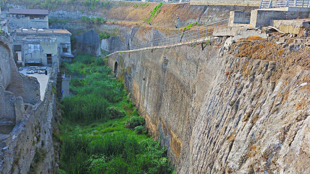 Herculaneum, photo taken between October 2014 and November 2019. 
Looking east along depth of solidified ash on south side of beachfront, with tunnel exit in centre left. Photo courtesy of Giuseppe Ciaramella.